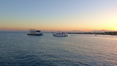 Luxury-yachts-near-tropical-coastline-beach-during-sunset,-pan-right-view