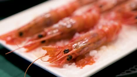 Vista-Estrecha-De-Un-Exquisito-Plato-Con-Camarones-Rojos-De-Mariscos-Cocidos-Al-Horno,-Presentados-En-Un-Plato-Blanco,-Acentuados-Por-La-Delicada-Adición-De-Sal-Marina.