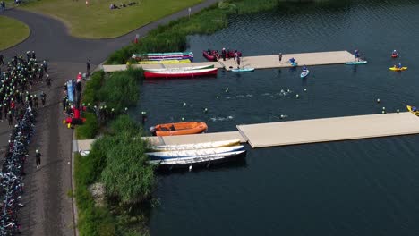 Drone-shot-of-Triathlon-at-Dorney-lake,-triathletes-are-beginning-the-race-and-swimming-towards-the-transition-area