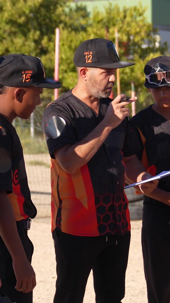 Baseballtræner giver instruktioner til unge spillere på banen.