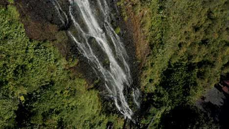 water cascading down lush mountain, cascada de la virgen in baños de agua santa, ecuador - drone shot
