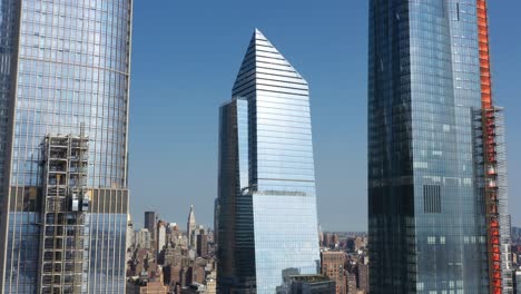 aerial drone truck right as the sun shines, glistens - reflects off of ten hudson yards and the other buildings at hudson yards in new york city