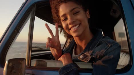 woman showing victory sign in pickup truck at beach 4k