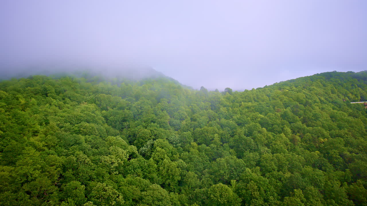 Mountains cloaked in mist seen from a cinematic drone flyover