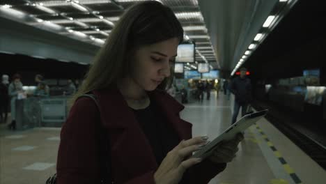 joven usando una tableta en la estación de metro