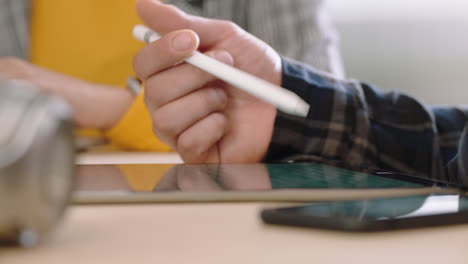 close up hands businessman using digital tablet computer showing business woman information poitnting stylus pen at screen on mobile touchscreen device