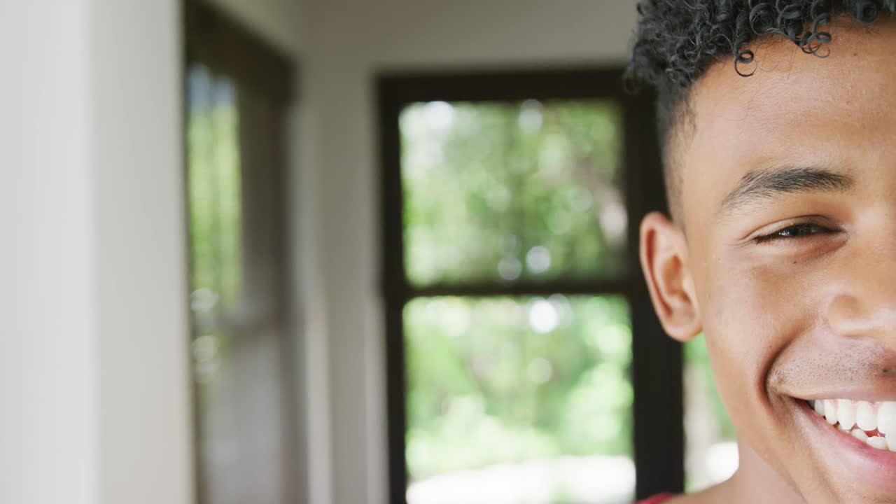 Portrait of happy african american male teenage boy at home, slow motion