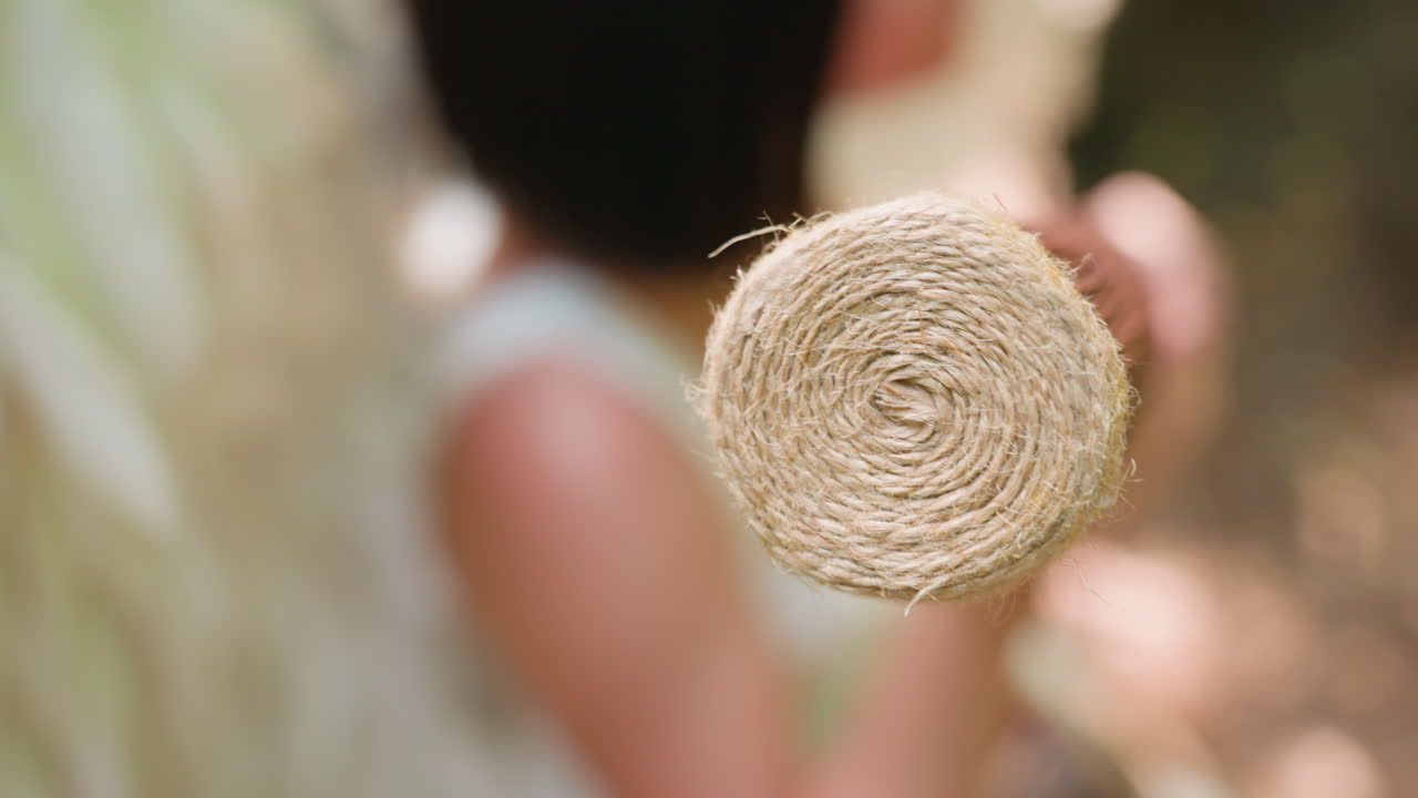 Extreme close up of fairy being rotating rope wrapped wooden staff gently under forest light, focus on spiral texture and motion, expressing harmony, elegance, craftsmanship, and mystical presence