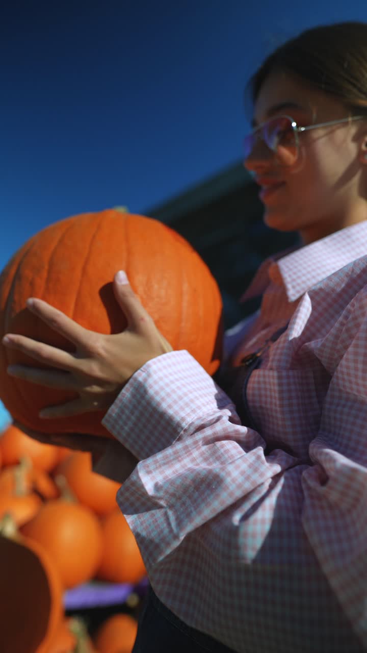 농장 시장 에서 큰 호박 을 들고 있는 여자