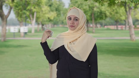 egoistic muslim woman using money as fan in park