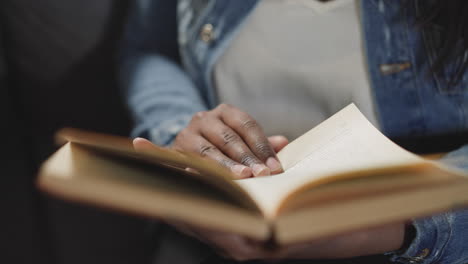 mujer hojea las páginas del libro de texto en busca de información