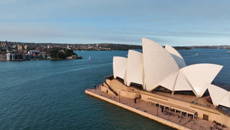 Aerial-View-Panning-From-Australian-Landmark-The-Sydney-Opera-House-To-Sydney-Harbour-Bridge-Behind-At-Sunset