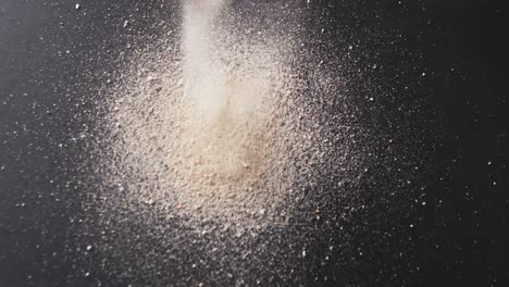 video of close up of sand grains pouring into heap and copy space on black background