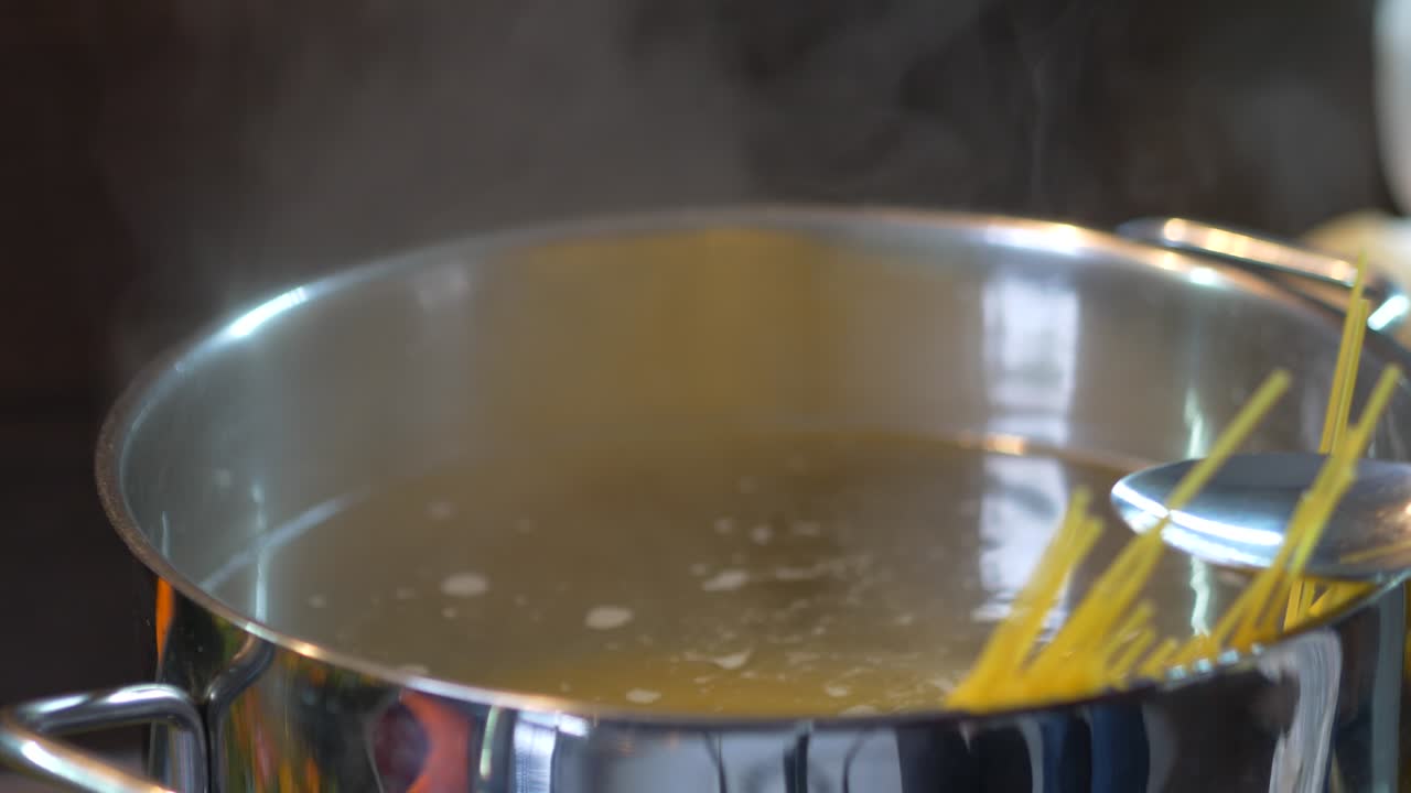 Spaghetti are stirred in boiling water with a spoon
