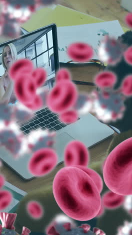 animación de células de covid-19 y glóbulos rojos sobre una mujer de negocios usando una computadora portátil