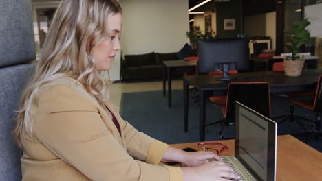 Plus-size-caucasian-casual-businesswoman-using-laptop-at-office-lounge