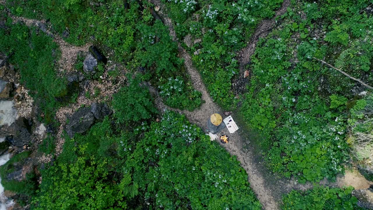 hombre con barba hace una ceremonia de fuego frente a una gran cascada