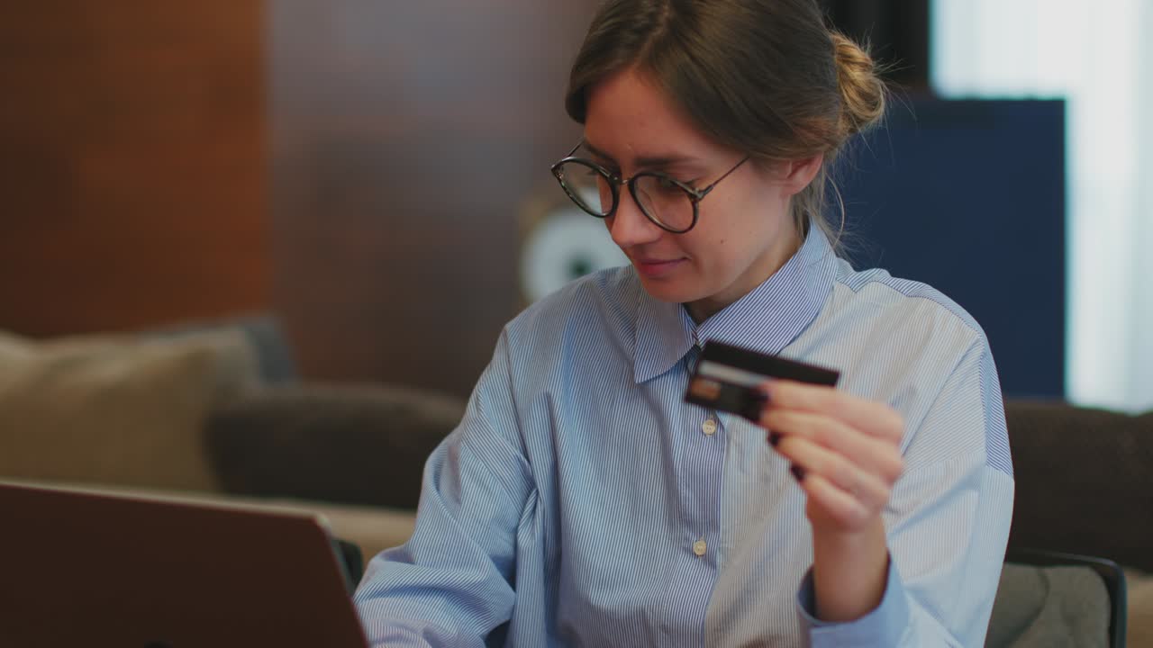 mujer feliz con gafas sosteniendo tarjeta de crédito bancaria, usando portátil, pagando en línea, ingresando información. servicio bancario
