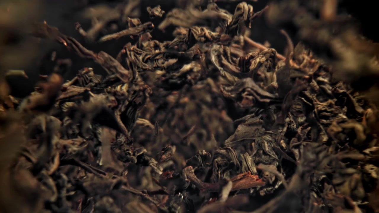 Dried Black Tea Leaves Falling in Slow Motion on a Dark Background
