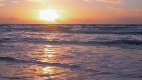 beautiful sunset on the background of baltic sea, sun going beyond the horizon illuminating water and clouds in the sky, calm sea waves, romantic mood, copy space, low wide shot