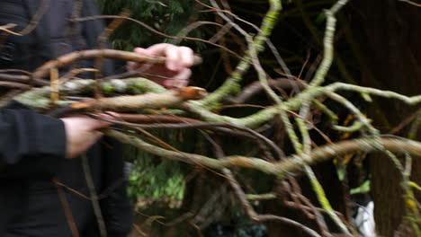 a man carrying tree brances and stick in the woods