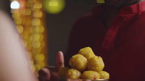 close up of man giving ladoo to woman to eat celebrating festival of diwali