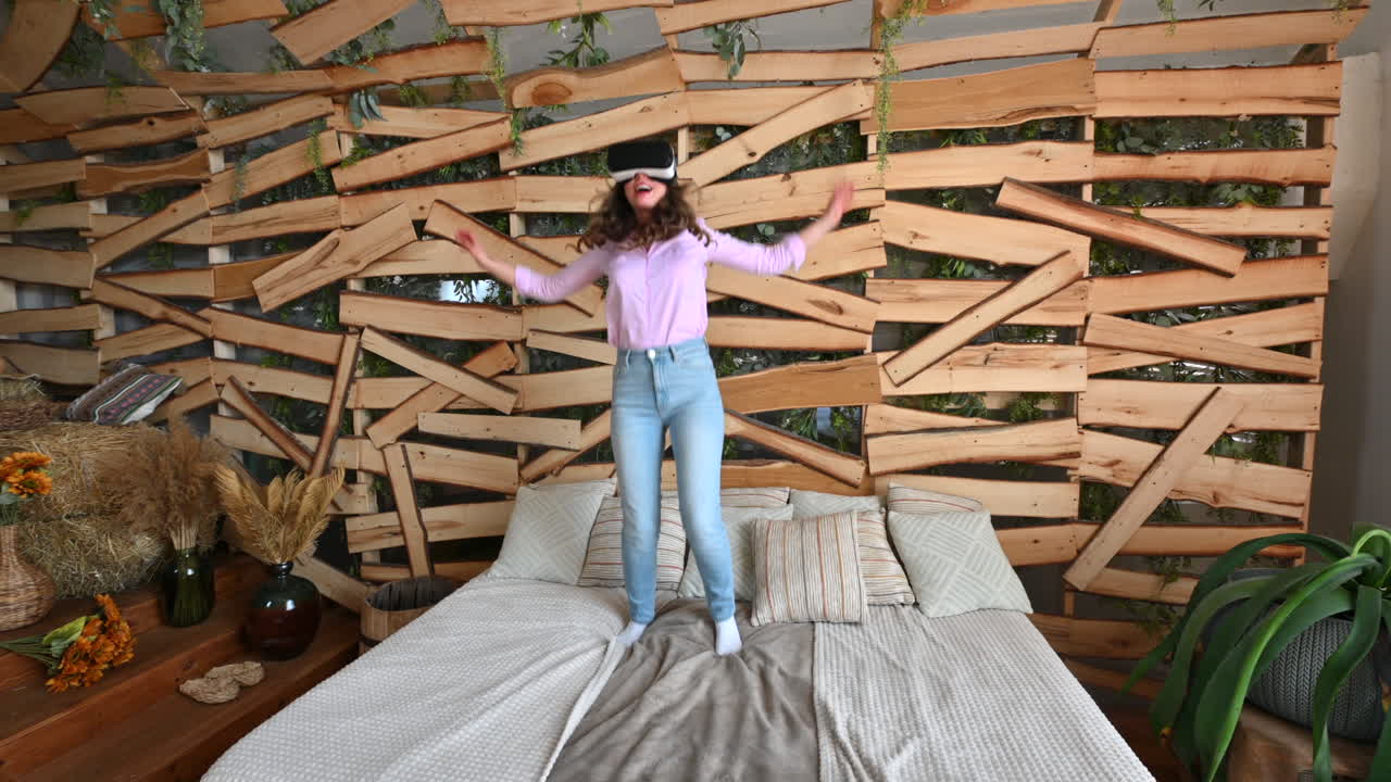 Woman looking through VR headset and jumping on bed