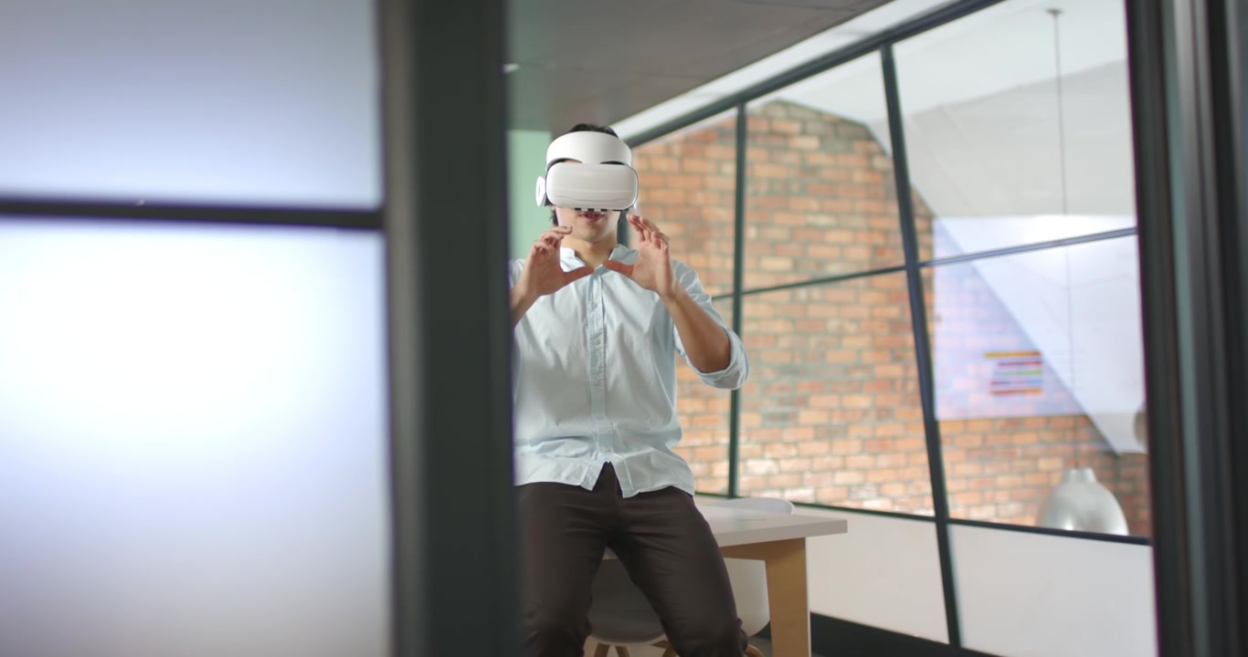 Lansering av VR-app, asiatisk mann i blå skjorte med VR-hodesett gestikulerer og undersøker modell ved skrivebord