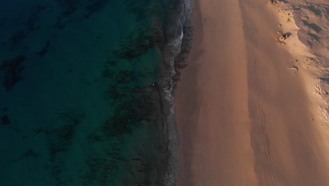 Lockdown-aerial-view-over-golden-sand-and-turquoise-waters-at-sunrise