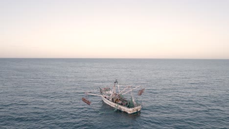 aerial shot drone shot circling shrimp boat while fishing at sunset