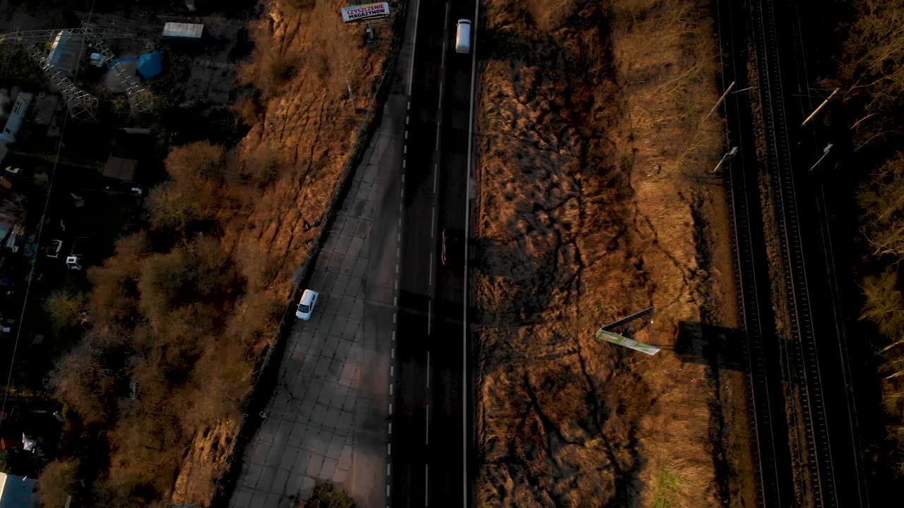 석양에 철도에 인접한 아스팔트 도로에서 운전하는 차량의 조감도