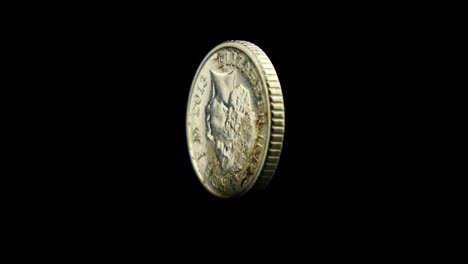 british five pence coin isolated and rotating in front of a black studio backdrop