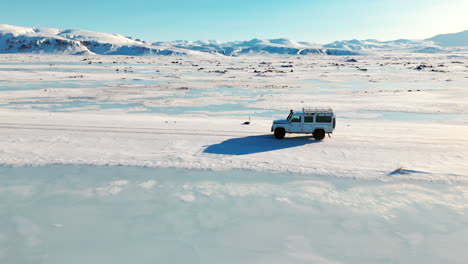 white jeep traveling across snowy icelandic highlands, side profile aerial