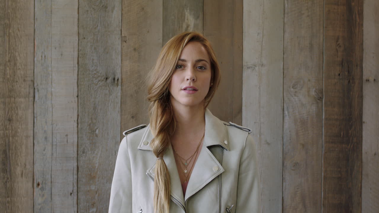 카메라를 보고 웃는 젊은 쾌활한  ⁇ 은 머리 여성의 초상화 나무 배경 로비에서 행복한 세련된 여성