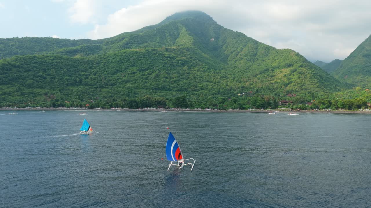 Traditional jukung boats sailing along amed coastline in bali