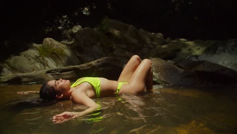 a caribbean waterfall serves as the backdrop for a bikini-wearing young girl
