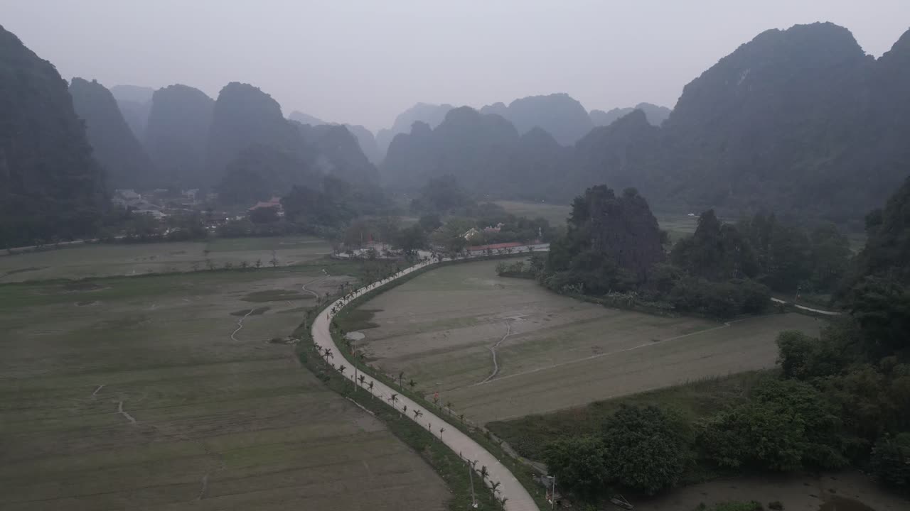drone shot of road weaving through rice fields and farms in the mountainous region of Ninh Ninh in Northern Vietnam