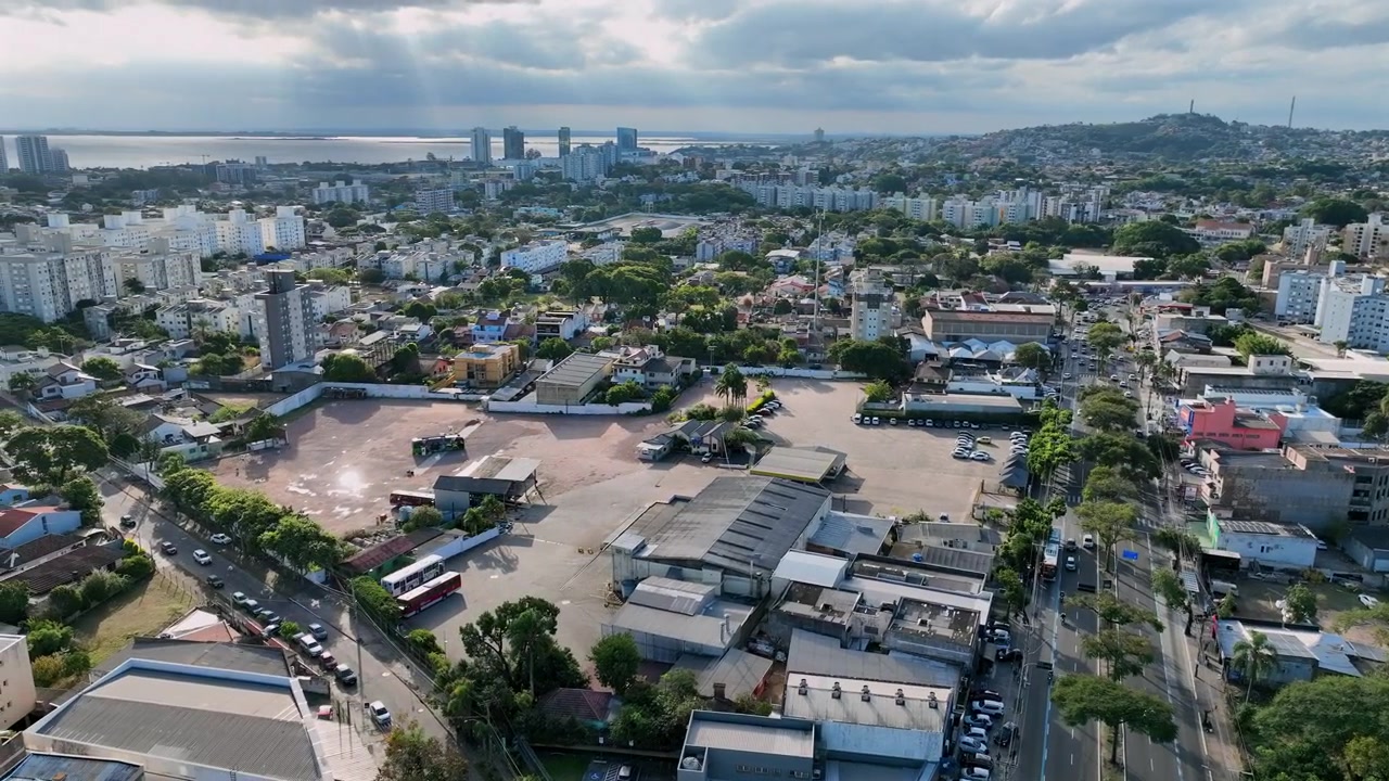 Panoramica aerea da destra a sinistra sopra Avenida Cavalhada a Porto Alegre, che mostra il viale alberato e il distante Lago Guaíba.