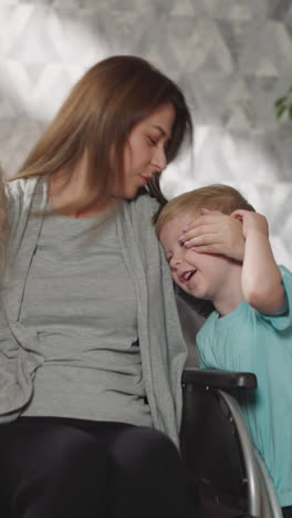 madre feliz con parálisis sentada en silla de ruedas abraza y besa a su hijo y su hija. mujer expresa amor a los niños pasando tiempo en casa