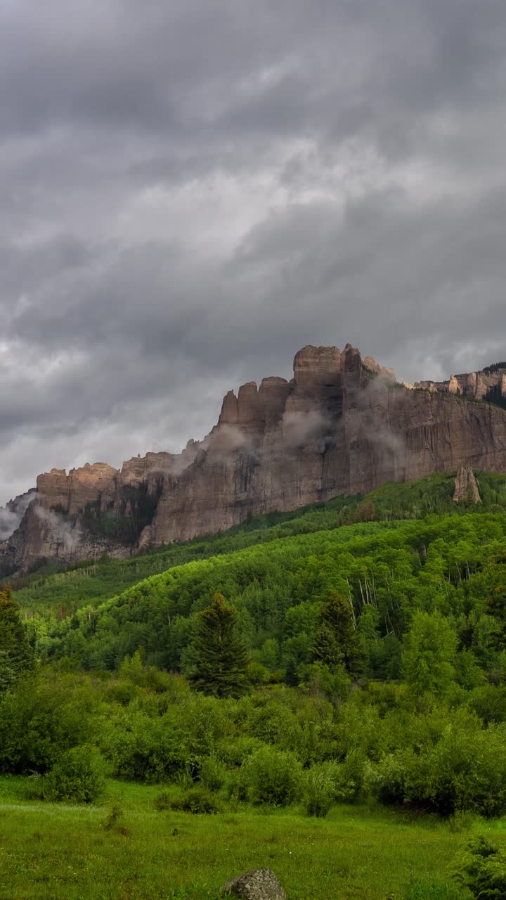 Vertical Time Lapse of Rocky Peaks and Clouds Above Green Mountain Landscape