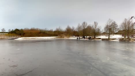 panoramic shot of a frozen pond and children ice skating