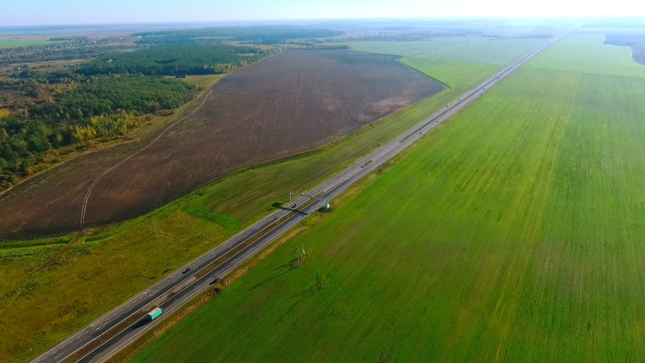 los coches conducen a lo largo de la carretera más allá de los campos verdes. tráfico de coches.