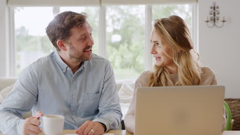 couple at home buying products or services online using laptop computer