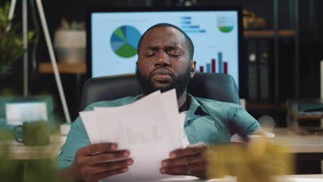 tired african guy drinking coffee in office