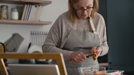 Mujer-Mayor-Caucásica-Pelando-Una-Zanahoria-Mientras-Cocina-En-La-Cocina