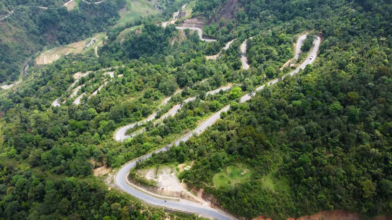 가파른 산악 경사 아래로 차량은 베트남의 휘어지는 도로를 여행합니다.