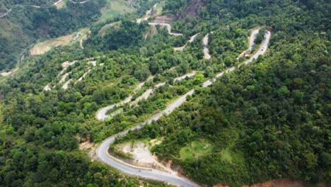 down a steep mountainous slope vehicles travel a winding road in vietnam