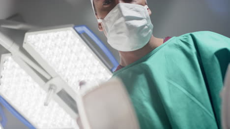 cirujano caucásico usando un desfibrilador en el quirófano del hospital, cámara lenta