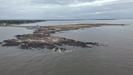 Flying-over-Penvins-coast-and-chapel-in-background-in-Morbihan-gulf-in-Brittany,-France