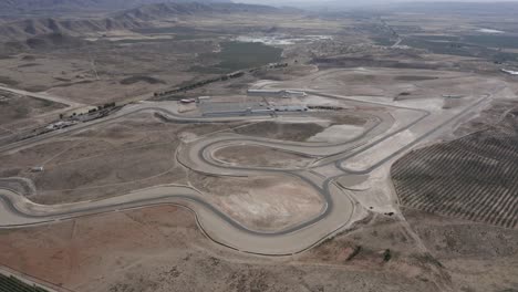 una pista de carreras de deportes de motor en europa rodeada de montañas y un desierto polvoriento